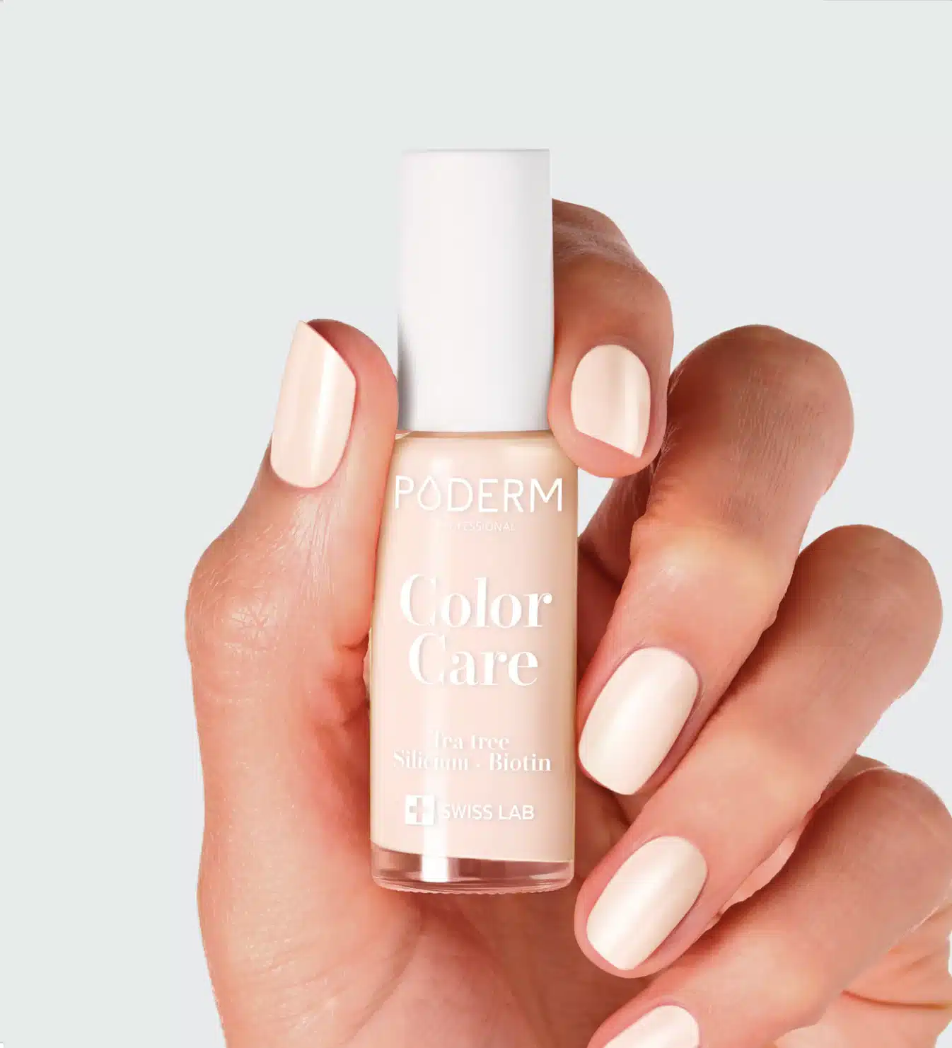 Main tenant un flacon beige clair "Color Care" devant ongles nude sur fond gris clair