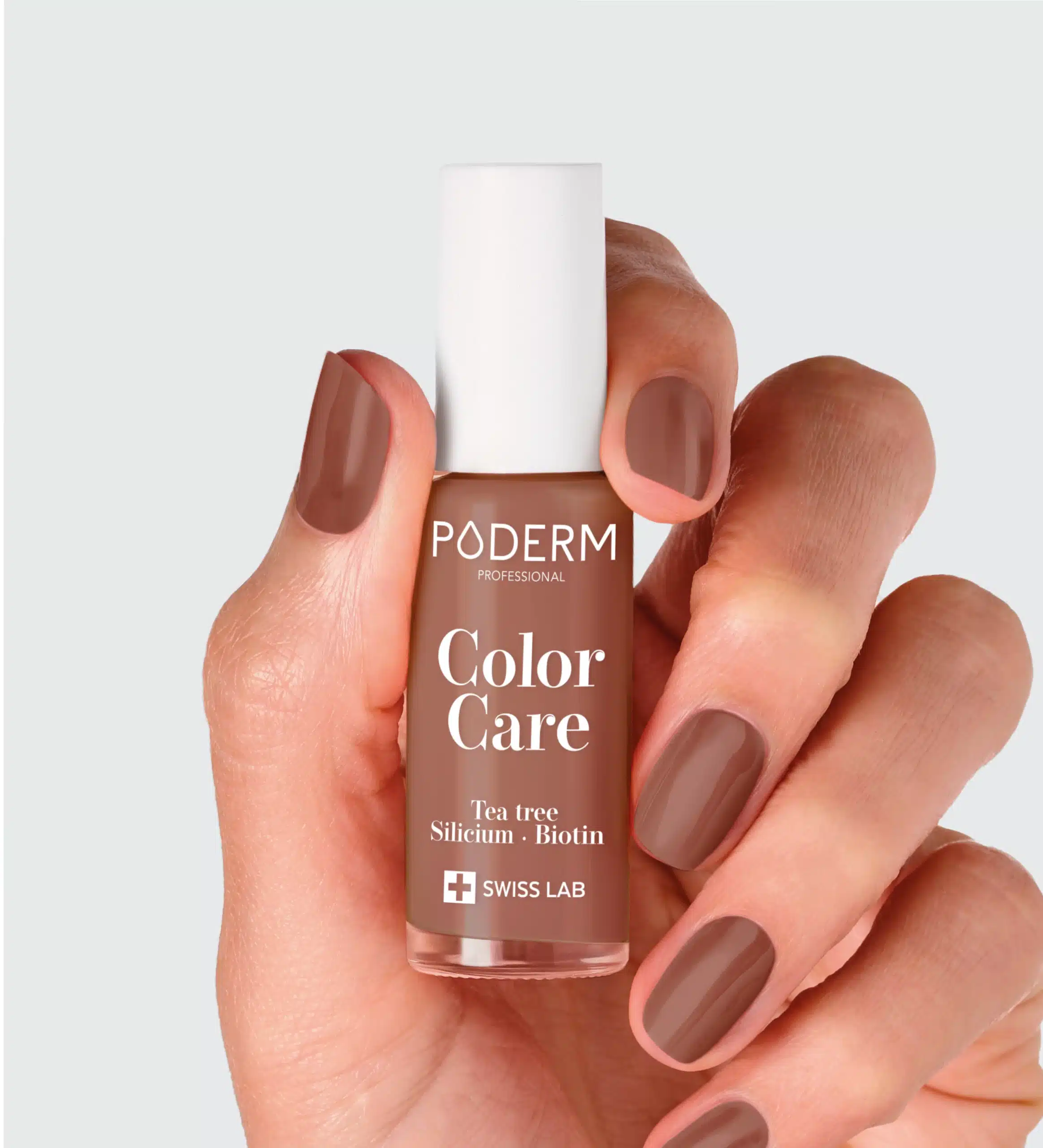 Mains tenant un petit flacon brun clair sur fond gris clair, vernis taupe, étiquette Color Care blanc