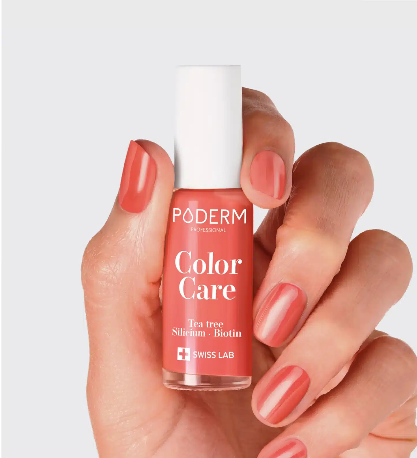 Main tenant un vernis rosé corail au capuchon blanc et ongles assortis PODERM Color Care