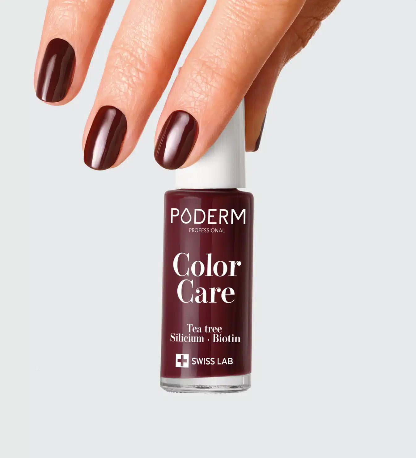 Écran de vernis rouge sombre entre des doigts sur fond gris clair